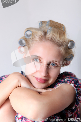 Image of  young woman with hair curlers on her head. 