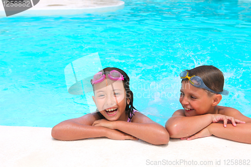 Image of Happy children,  girl and boy, relaxing on the side of a swimmin