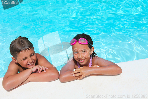 Image of Happy children,  girl and boy, relaxing on the side of a swimmin