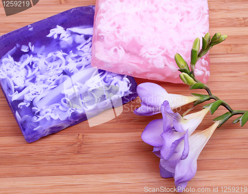 Image of Lilac and pink soap on wooden background in a spa composition 
