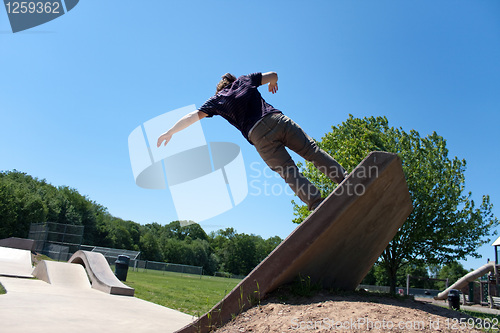 Image of Skateboarder Riding Up a Concrete Skate Ramp