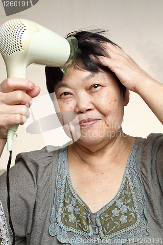 Image of female drying her hairs with drier