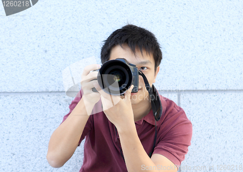 Image of young teenage photographer taking a photo with his DSLR camera. 