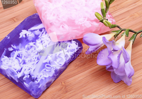 Image of Lilac and pink soap on wooden background in a spa composition 