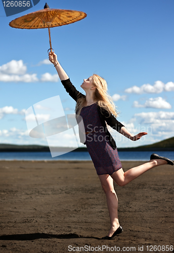 Image of blonde girl with an Oriental umbrella against the sky and mounta