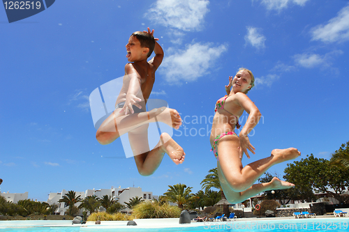 Image of boy with mum jumping into the pool smiling 