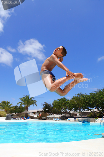 Image of boy jumping into the pool smiling 