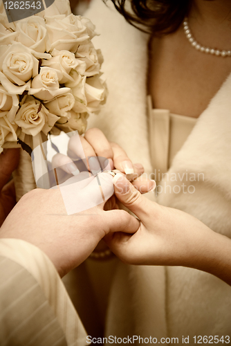 Image of puttting on a wedding ring. stylized photo