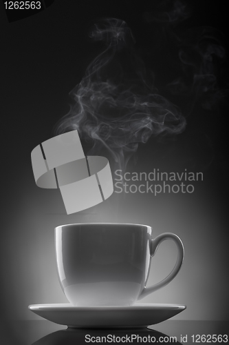 Image of white cup with hot liquid and steam on black
