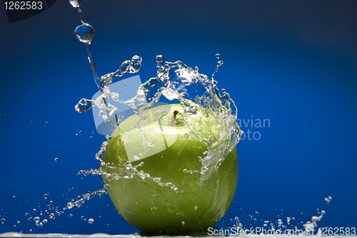 Image of Green apple with water splash on blue background
