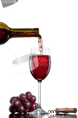 Image of Red wine pouring into glass with grape isolated on white