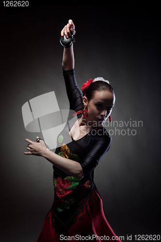 Image of young woman dancing flamenco with castanets on black