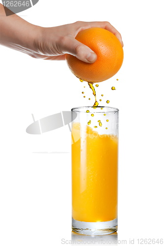 Image of squeezing orange juice pouring into glass isolated on white