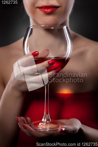Image of woman in red holding wine glass and smiles