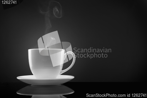 Image of white cup with hot liquid and steam on black