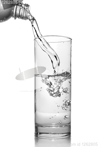 Image of water pouring into glass from bottle isolated on white