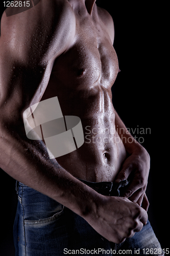 Image of Posing muscular naked man with body in water drops on black