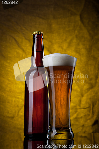 Image of Beer in glass with bottle on yellow background