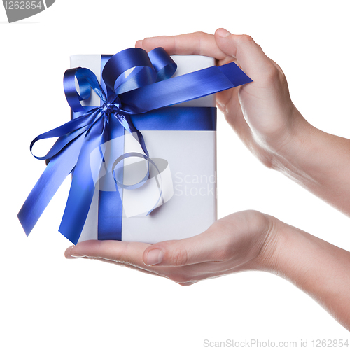 Image of Hands holding gift in package with blue ribbon isolated on white