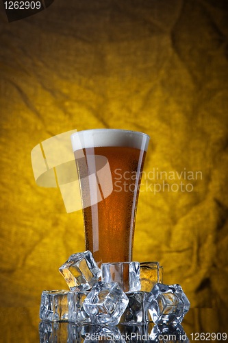 Image of Beer in glass with ice cubes on yellow background