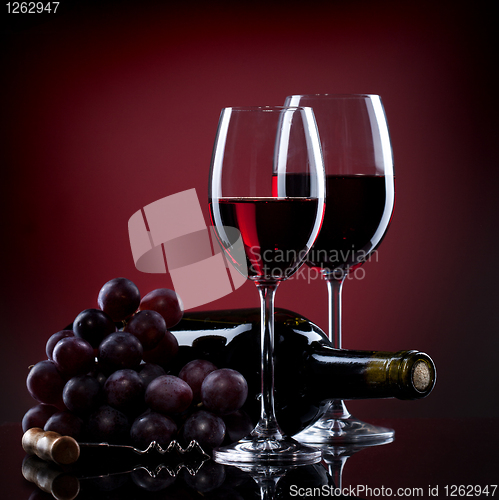 Image of Wine in glasses with grape and bottle on red