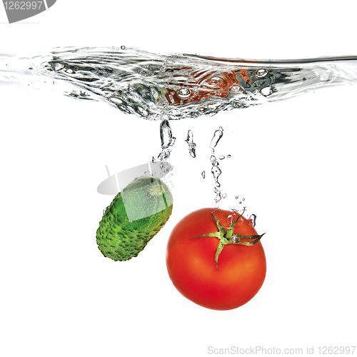 Image of red tomato and green cucumber dropped into water isolated on whi