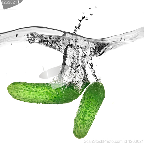 Image of green cucumbers dropped into water isolated on white