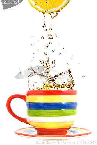 Image of lemon, color cup and splash of tea isolated on white