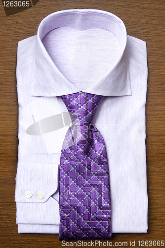 Image of shirt with violet tie on wooden shelf