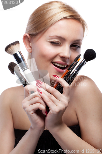 Image of Young smiling woman with make up brushes isolated on white