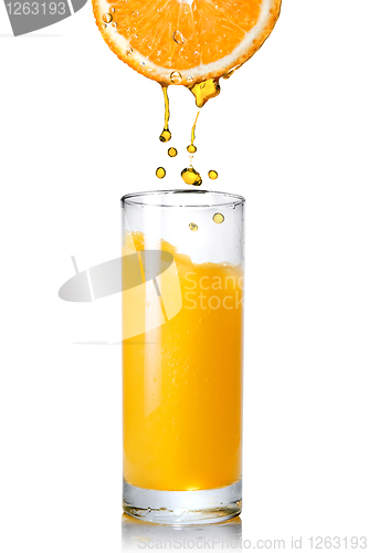 Image of Pouring orange juice from orange into the glass isolated on whit