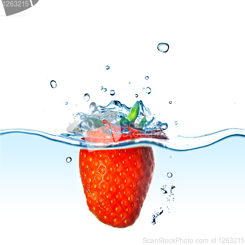 Image of Fresh strawberry dropped into blue water with splash isolated on