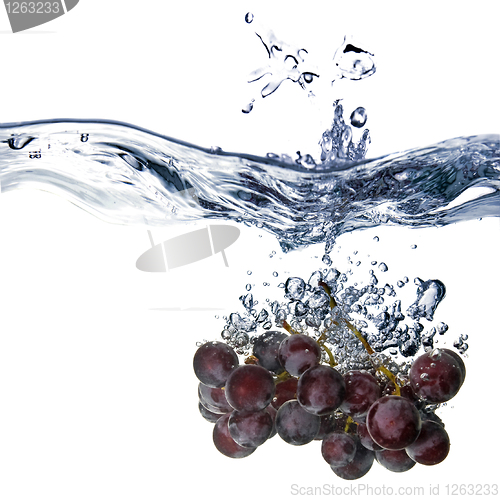 Image of blue grape dropped into water with splash isolated on white