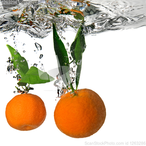 Image of tangerine dropped into water with bubbles on white