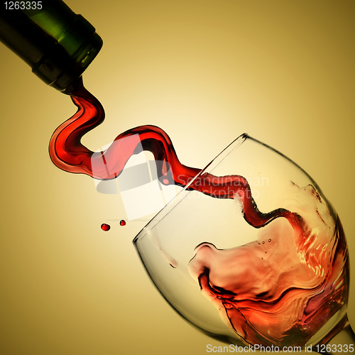 Image of Pouring red wine in goblet on yellow background