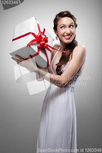 Image of Young surprised smiling woman holding gift 