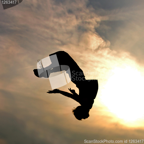 Image of silhouette of jumping man against sky and clouds