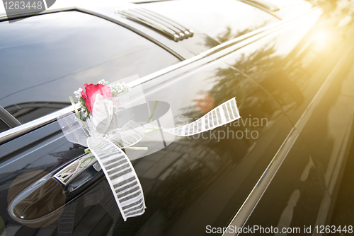 Image of Door of black wedding car with flower and ribbon