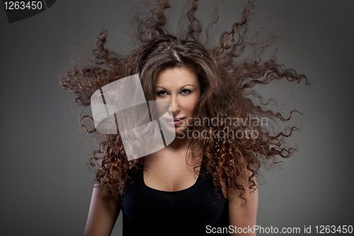 Image of portrait of beautiful woman with curly hair in air