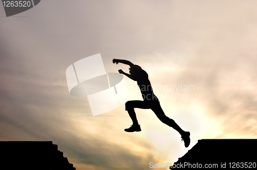 Image of silhouette of jumping boy agains