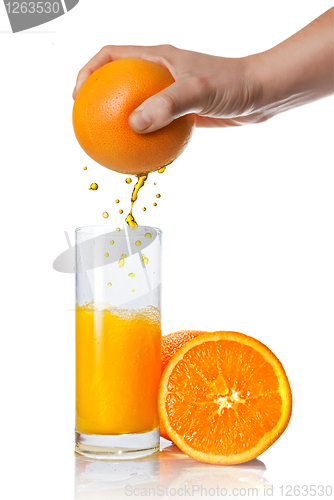 Image of squeezing orange juice pouring into glass isolated on white