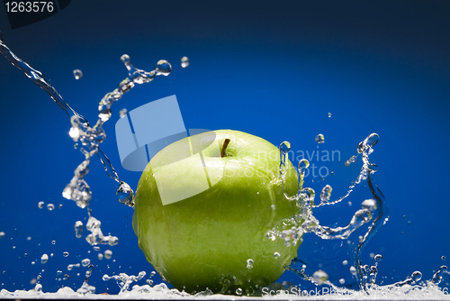 Image of Green apple with water splash on blue background
