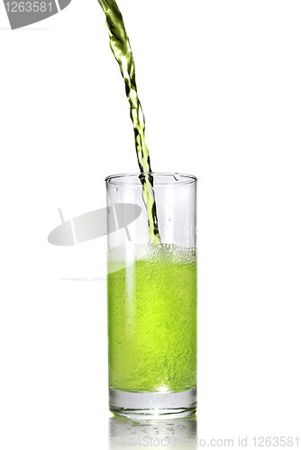 Image of green juice pouring into glass isolated on white