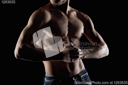 Image of Muscular naked man on black. Focus and hands
