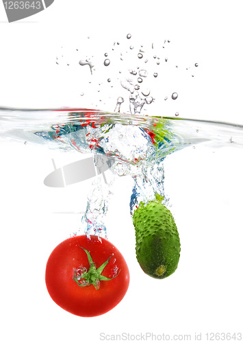 Image of red tomato and green cucumber dropped into water isolated on whi