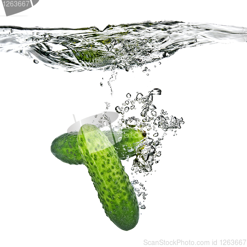 Image of green cucumbers dropped into water isolated on white