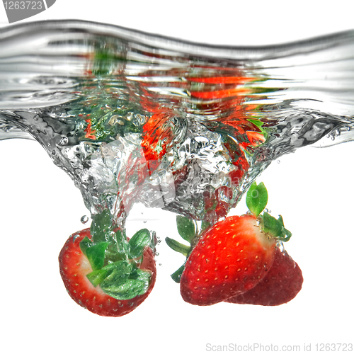 Image of Fresh strawberry dropped into water with splash isolated on whit