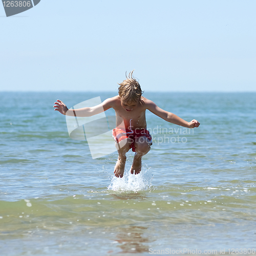 Image of Boy jumps over wave