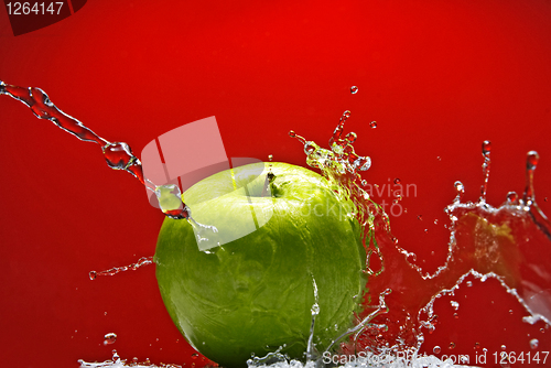 Image of Green apple with water splash on red background