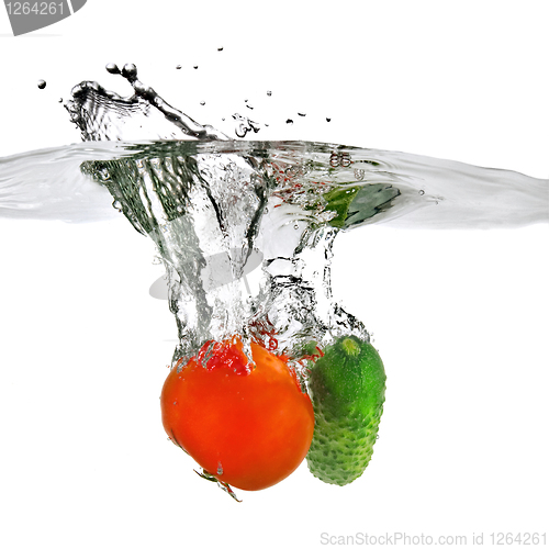 Image of tomato and cucumber dropped into water isolated on white